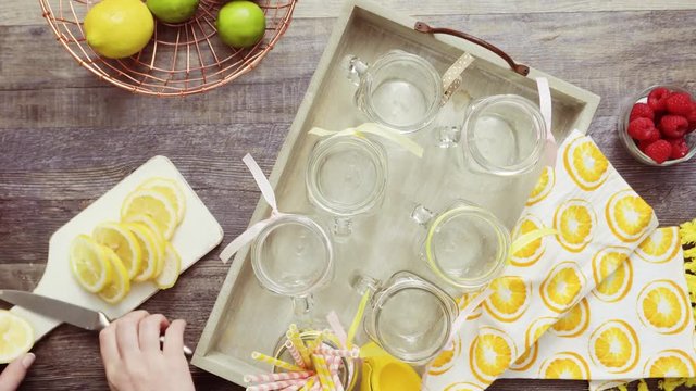 Step by step. Pouring raspberry lemonade with fresh lemons and raspberries in drinking mason jars