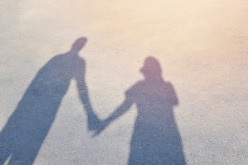 Shadow men and women stand hold hands on a bright day .