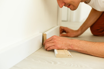 Man putting new skirting board in house