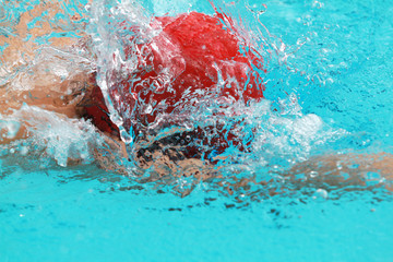 Close up young boy swimmer with red cap swim free style or forward crawl in a swimming pool for competition or race