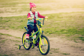 Child riding bike. Kid on bicycle in sunny park. Little girl enjoying bike ride on her way to...