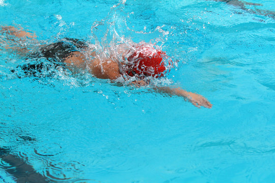 Boy Swimmer with Red Cap Swim Free Style or Forward Crawl in a Swimming Pool for Competition or Race