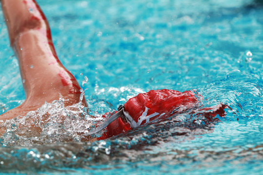 Close up young boy swimmer with red cap swim free style or forward crawl in a swimming pool for competition or race