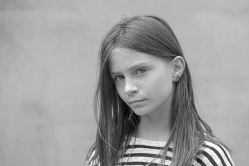 Beautiful blond young girl with freckles outdoors on wall background, closeup portrait, black and white