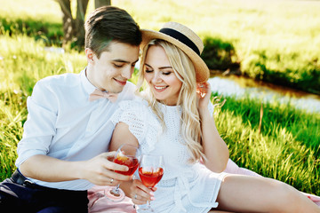 love, dating, people and holidays concept - happy couple drinking champagne on picnic over sunset background