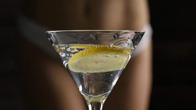 sexy young woman in a white panties prepares a cocktail with lemon in a dark. close-up buttocks and hip. slow motion