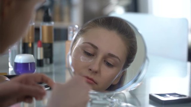 Girl removing patches from skin around eyes, effective help to face skin beauty