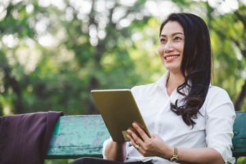 Asian business people woman using smartphone/tablet for online and internet for working at park outdoor