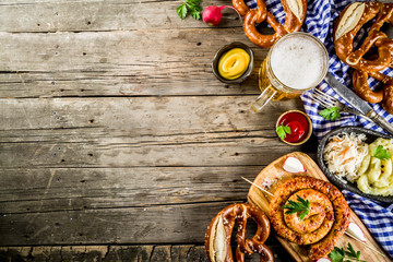 Oktoberfest food menu, bavarian sausages with pretzels, mashed potato, sauerkraut, beer bottle and mug old rustic wooden background, copy space above