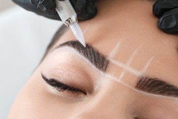 Young woman undergoing procedure of eyebrow permanent makeup in beauty salon, closeup - obrazy, fototapety, plakaty