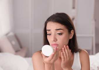 Young woman with eyelash loss problem looking in mirror indoors