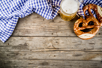 Oktoberfest food menu, bavarian pretzels with beer mug, old rustic wooden background, copy space above