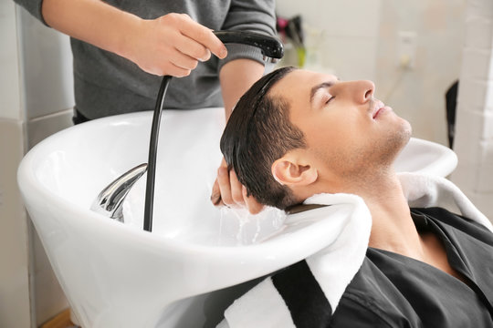 Hairdresser washing client's hair in beauty salon