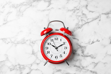 Alarm clock on marble background, top view. Time management