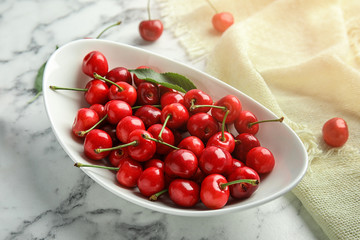 Bowl with sweet red cherries on marble table