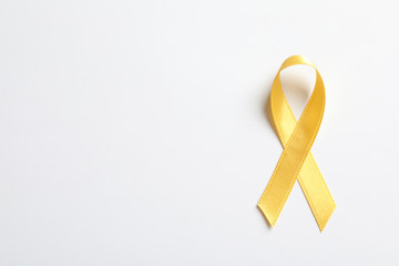 Yellow ribbon on white background, top view. Cancer awareness