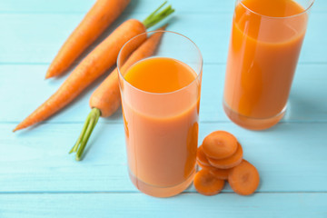 Glasses with carrot juice and fresh vegetable on wooden table