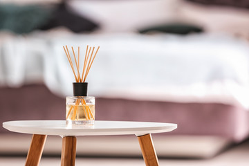 Aromatic reed air freshener on table against blurred background