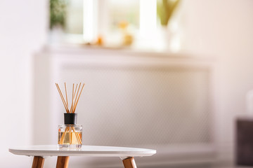 Aromatic reed air freshener on table against blurred background