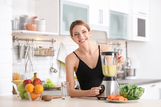Young woman preparing tasty healthy smoothie at table in kitchen