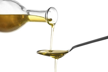 Pouring fresh olive oil into spoon on white background