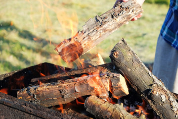 Man putting wood into metal brazier outdoors, closeup