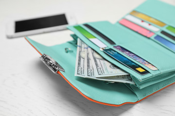 Stylish wallet with cash and credit cards on light background, closeup