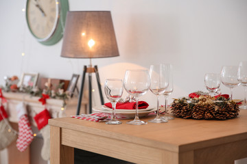 Set of dinnerware and Christmas wreath on table indoors