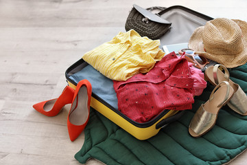 Open suitcase with clothes and accessories on floor