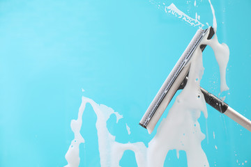 Cleaning glass with squeegee on color background