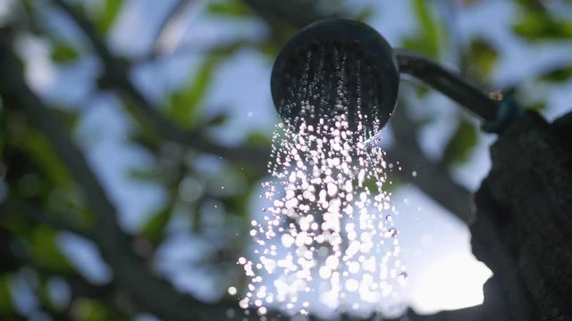 Outdoor beach shower with fresh water on beautiful blue sky background through the sunshine with leaves and lens flare effects. slow motion. 3840x2160