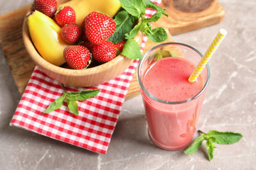 Glass with tasty strawberry smoothie and fresh fruits on table