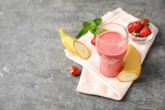 Glass with tasty strawberry smoothie and fresh fruits on table