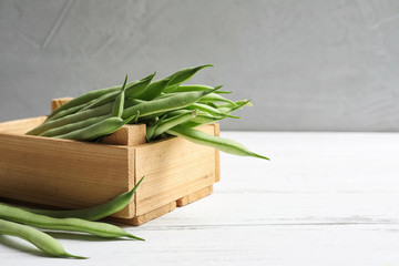 Wooden crate with fresh green beans on table
