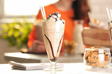 Glass with delicious milk shake on table indoors