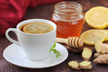 Cup of ginger tea with honey and lemon on wooden table