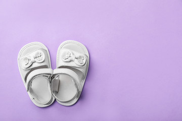 Pair of cute baby sandals on color background, top view
