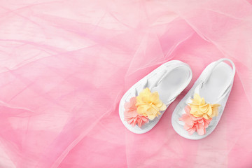 Pair of cute baby sandals on color fabric, top view