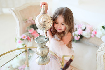 Little girl dressed like a princess pours tea in the vase while playing