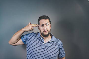 handsome young man pretending to shoot himself with his hand as a gun