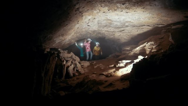 Children in helmets with lanterns comes into a dark cave