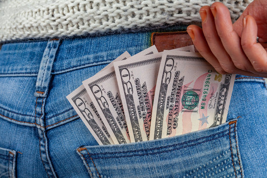 Female Hand Reaching For 50 US Dollar Bills In Her Jeans Back Pocket