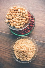 Crushed peanuts or mungfali powder with whole and roasted groundnut. Served in a bowl over moody background. Selective focus