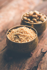 Crushed peanuts or mungfali powder with whole and roasted groundnut. Served in a bowl over moody background. Selective focus
