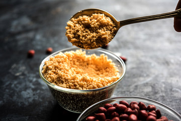 Crushed peanuts or mungfali powder with whole and roasted groundnut. Served in a bowl over moody background. Selective focus