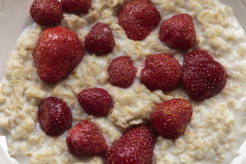 Hot oatmeal porridge with cream and fresh strawberries. Healthy breakfast concepts.