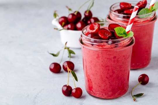 Cherry smoothie in glass with mint leaves and fresh berries