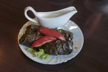 A Greece appetizer of stuffed vine leaves served on a white plate in a restaurant.