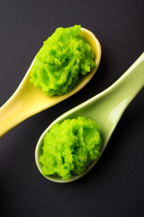 Green wasabi sauce or paste in bowl, with chopsticks or spoon over plain colourful background. selective focus