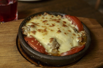 Meat in a frying pan, baked with vegetables and cheese. Dish of Mediterranean cuisine. Restaurant shooting.